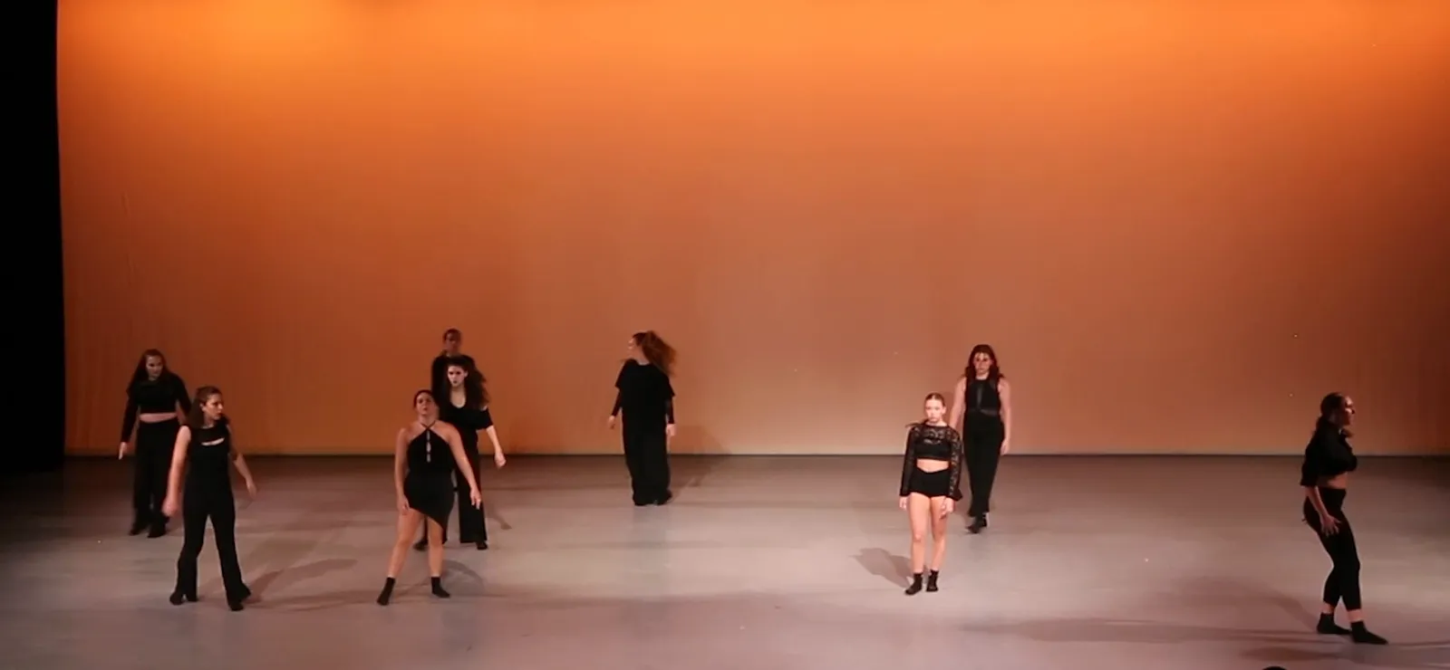 Adult dancers in black spread across the stage at Amusing Spaces, 2025